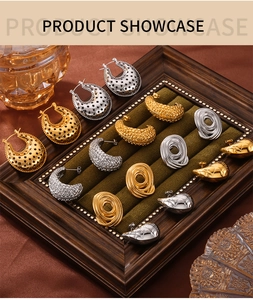 Close-up of assorted gold and silver geometric earrings on a green velvet jewelry tray