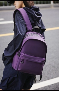 Outdoor view of a large capacity purple nylon backpack with MUMU logo and front zip pocket