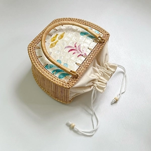 Detail van gevlochten rotan tas met kleurrijk schelpenmozaïek en beige stoffen voering