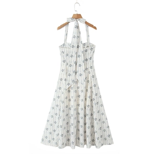 Detail of white floral halter dress with open back and blue ribbon bow tie on wooden hanger