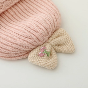 Bonnet en tricot rose pour bébé avec nœud blanc, broderie cerise et tresses perruque