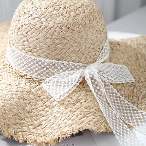 Handwoven straw hat with wide brim, lace ribbon bow and frayed edges for beach vacations
