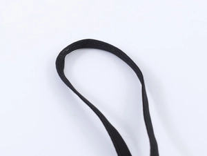 Vue macro détaillée montrant les coutures fines sur la bretelle en tissu noir de la robe