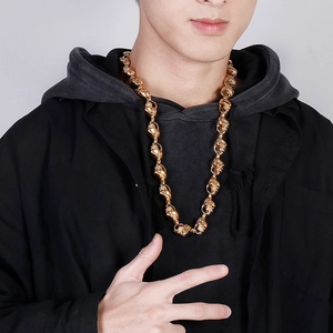 Detail of a bold gold punk skull necklace chain worn by a male model on black jacket