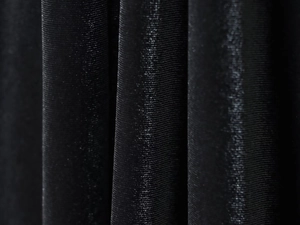 Dettaglio macro del tessuto in velluto nero con pieghe verticali e lucentezza sottile