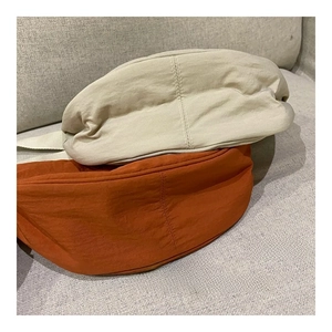 Close-up of nylon beret hats in beige and caramel orange with double stitching detail
