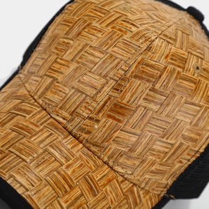 Macro shot of brown straw texture and black mesh stitching on a breathable trucker hat