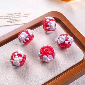 Macro detail of red resin beads with 3D embossed purple floral patterns for DIY jewelry