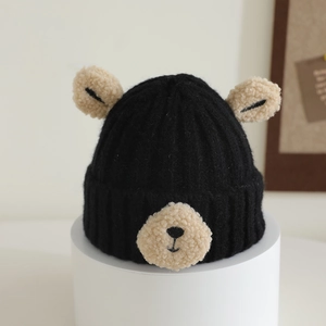Close-up of a black knitted winter hat with cute plush 3D bear ears for kids