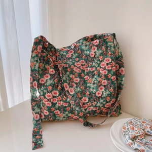 Detail of green floral canvas tote bag featuring pink blossom print and white button closure