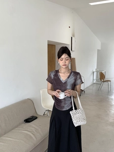 Close-up of white woven straw handbag paired with a tie-dye V-neck T-shirt and black skirt