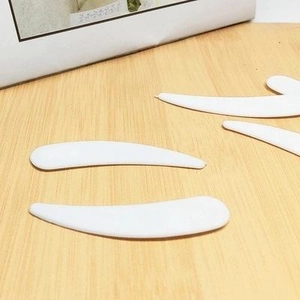 White plastic curved cosmetic spatula for face cream and skin care application