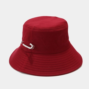 Dettaglio ravvicinato del cappello alla pescatora rosso scuro con spilla di strass lucenti
