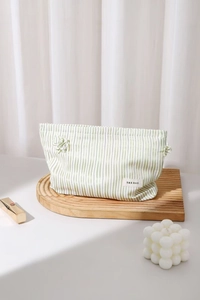 Dettaglio della borsa da trucco in tessuto a righe verdi con etichetta H & R BAG e laccio