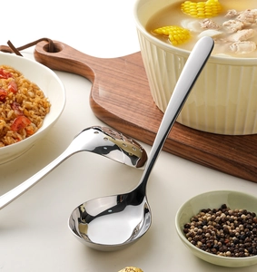 Polished stainless steel ladle and skimmer set serving hearty corn and rib soup