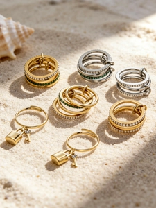 Detail of 18K gold plated stackable rings with green zircon and lock pendant jewelry