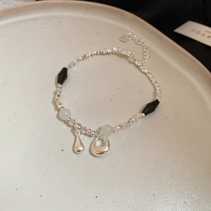 Dettaglio di un braccialetto di perle con ciondolo a cuore, zircone ed ematite su un vassoio