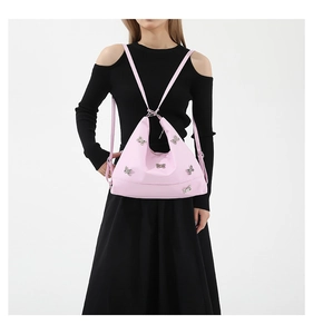 Pink nylon shoulder bag with bow detail worn by a model in a black dress