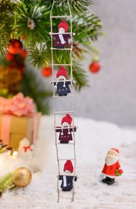 Close-up of four wool felt Christmas elves climbing a rope ladder next to a tree