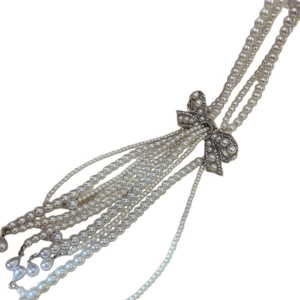 Elegant multi-layer pearl necklace with rhinestone bow pendant on white background