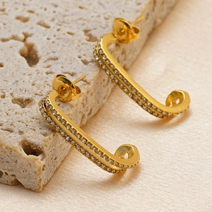 Golden double-layer U-shaped earrings with micro-paved rhinestones on stone background