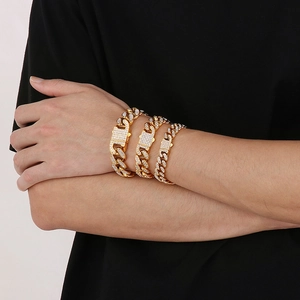 Three-piece set of golden iced-out Cuban link bracelets with rhinestones on model wrist