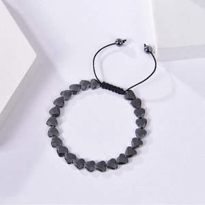 Detail showing heart-shaped black hematite beads on a black woven adjustable bracelet