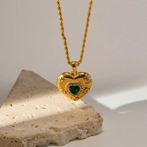 Vintage heart necklace with green zircon in gold lava texture on a rustic stone base