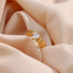 Detail of 18K gold plated stainless steel ring with heart zircon on pink silk fabric
