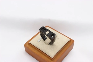 Macro shot of polished black ring with GOD lettering displayed on a wooden jewelry stand