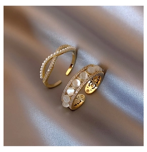 Detailed view of gold cross rings with pearls and cat eye stones on champagne silk