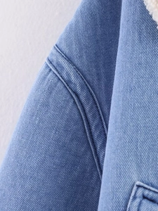 Detail of blue denim jacket showing thick fabric texture and white fleece collar lining