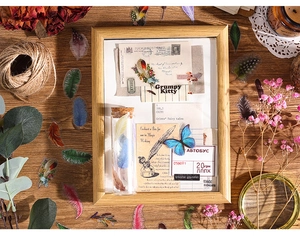 Vintage craft stickers with feathers and butterflies on a wooden desk with dry flowers
