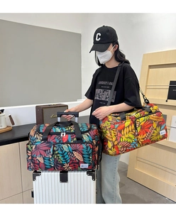 Spacious travel tote bag with colorful leaf print and luggage sleeve shown on a model