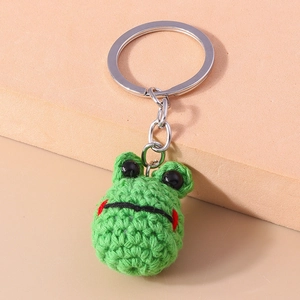 Detail of a handmade green crochet frog keychain with soft knit texture and metal ring