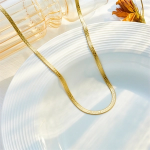 Gold plated stainless steel blade chain necklace elegantly displayed on a white textured plate
