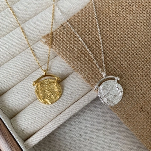 Dettaglio di ciondoli a moneta vintage in oro e argento con rilievo in una scatola portagioie
