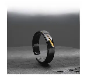 Detail of black open ring with golden lava texture on a natural stone background