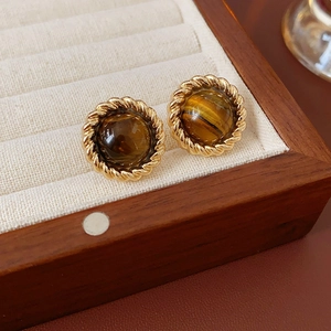 Gros plan de boucles d'oreilles vintage dorées avec pierre œil de tigre sur velours