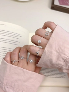 Close-up of assorted S925 sterling silver rings with heart and knot designs on hand