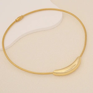 Macro detail of a polished gold crescent pendant on a snake chain necklace set