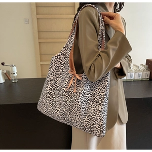 Detail of leopard print shoulder bag featuring a stylish pink bow tie and soft fabric texture