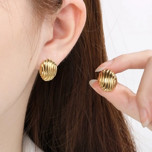 Vintage gold hollow round stainless steel earrings with textured vertical ridges on model