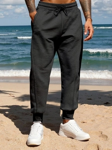 Detail of black joggers with drawstring waist and textured knit fabric on beach