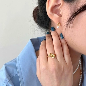 Detail view of model wearing a gold twisted ring, pearl drop earrings and a pearl necklace