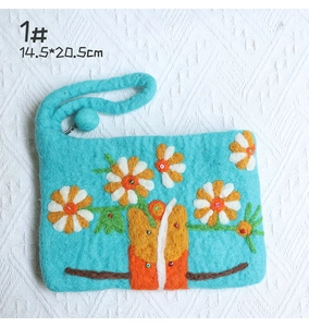 Detail of handmade blue wool felt pouch with orange daisy embroidery and beadwork