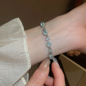 Detail of silver bracelet with aquamarine heart gems and bow-shaped zircon clusters
