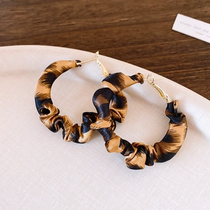 Detailed close-up of hoop earrings featuring retro leopard print fabric and gold metal
