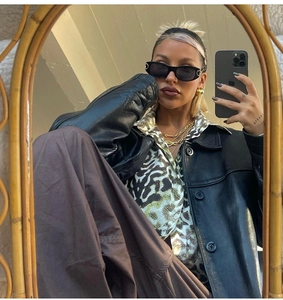 Fashionable punk oval sunglasses styled with chunky gold chain and black leather jacket