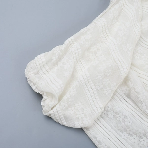 Detailed close-up of white lace sleeve cuffs with elegant floral embroidery pattern